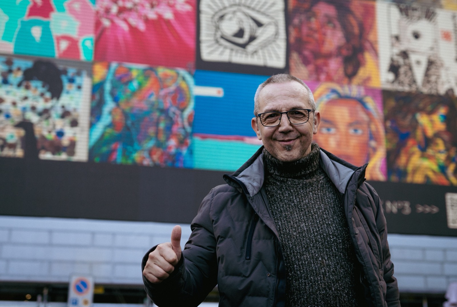 Un artiste devant son œuvre affichée en grand dans la ville